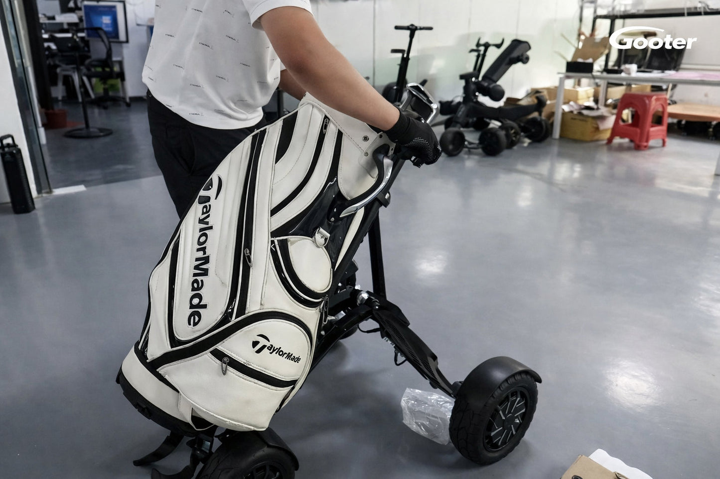 Person zieht den GOOTER E-CadPro mit Golfbag im Innenbereich